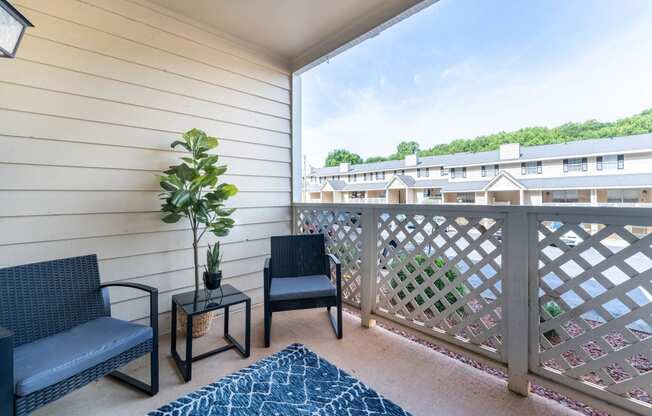 a balcony with two chairs and a potted plant