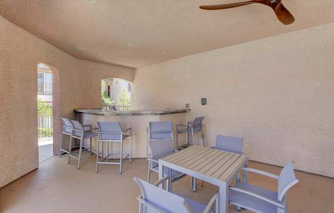 A patio with a table and chairs and a fan.