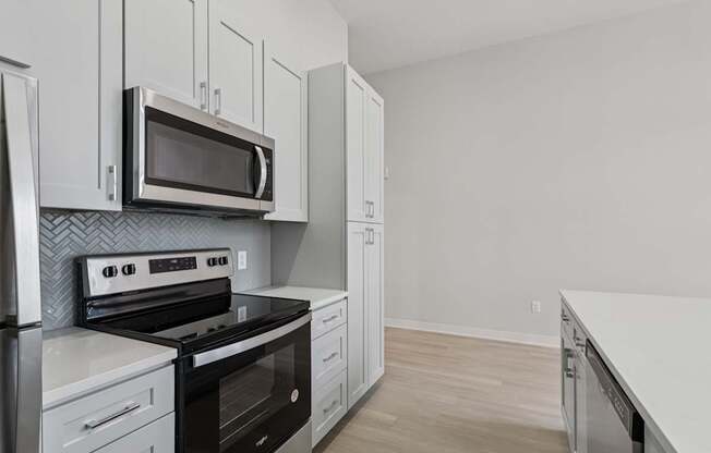 A kitchen with a stove, oven, microwave, and cabinets.