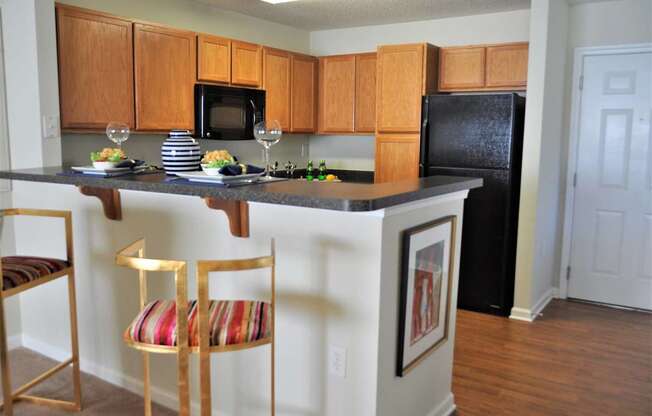 A kitchen with a black refrigerator and wooden cabinets.