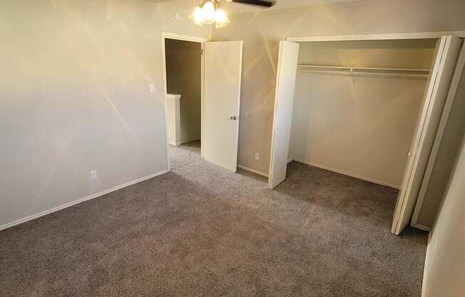 an empty living room with a ceiling fan and empty closets