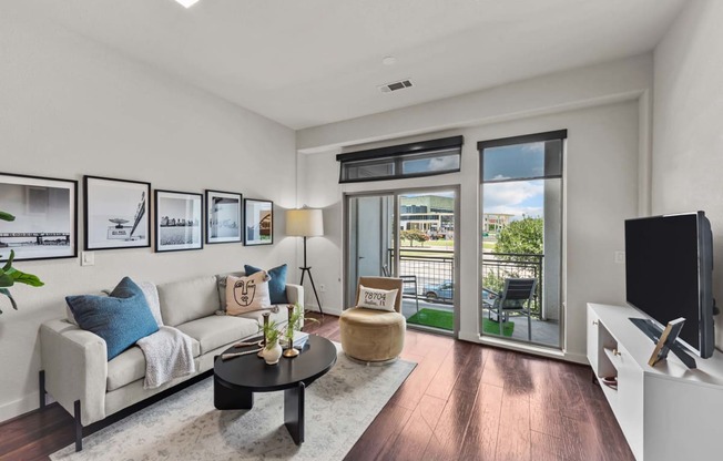 a living room with a couch and a tv and a balcony