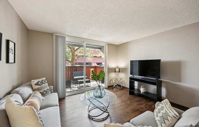 A living room with a grey couch and a glass coffee table.