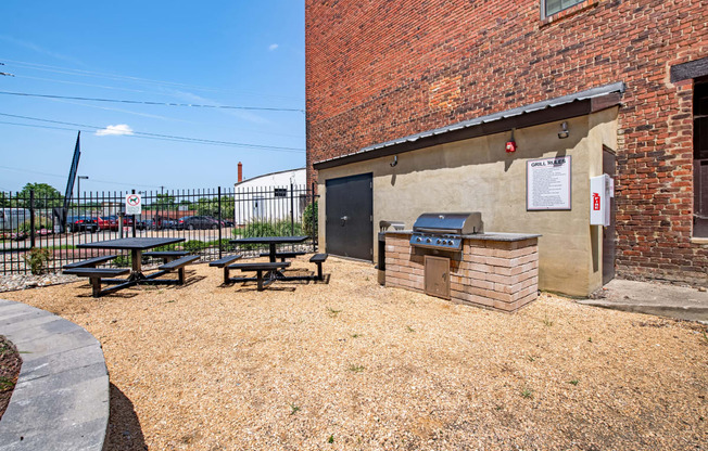 a picnic area outside of a brick building with a grill and picnic table