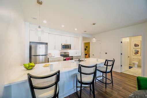 a kitchen with white cabinets and a large island with chairs