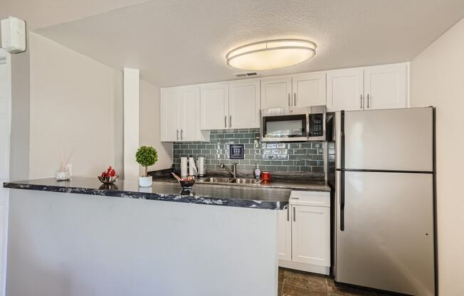 a kitchen with white cabinets and stainless steel appliances