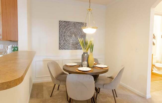 A dining room with a table set for two and a decorative piece hanging above it.