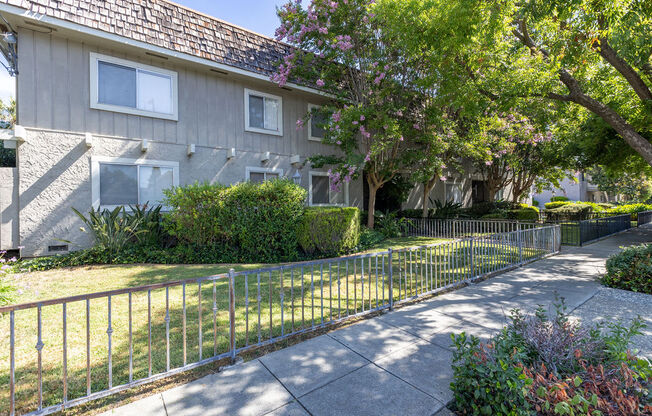 a white house with a yard behind a metal fence