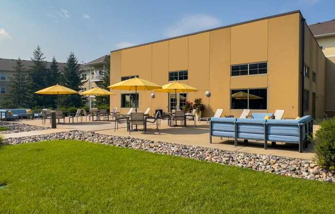 an outdoor patio with tables and umbrellas at chaska place apartments in chaska mn