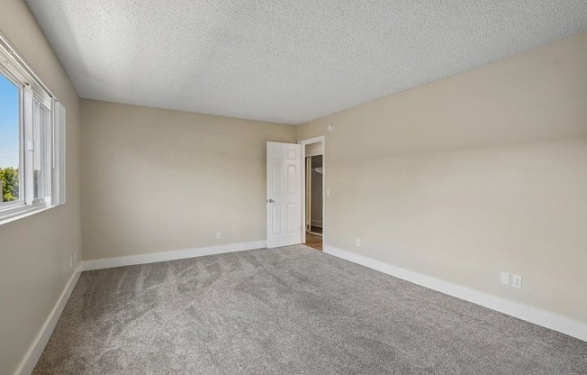 A room with a carpeted floor and a door leading to another room.
