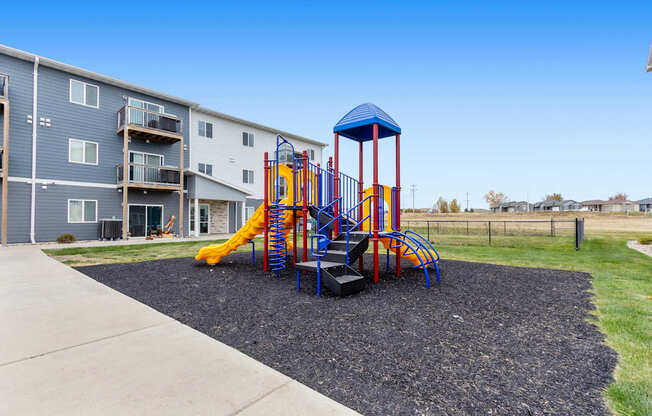 A playground with a blue and yellow slide and a red and blue tower.