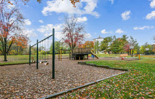 A playground with a swing set and a slide in the middle of a park.