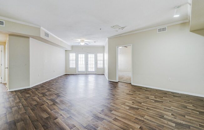 an empty living room with a hard wood floor and white walls