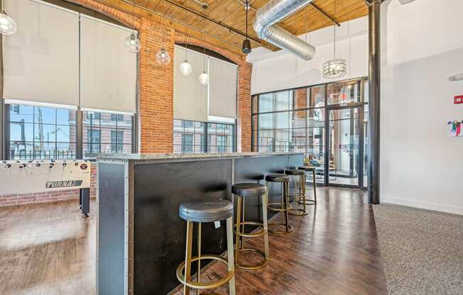 a long bar with stools and a exposed brick wall and glass doors