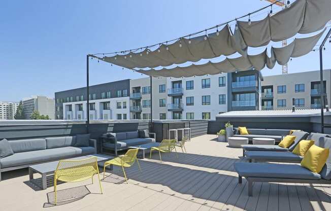 a roof deck with couches and chairs in front of a building with a crane in the