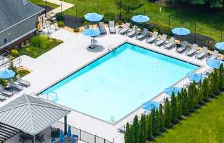 A large outdoor swimming pool surrounded by lawn chairs and umbrellas.