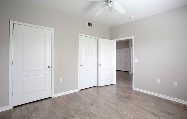 A room with a ceiling fan and three doors.