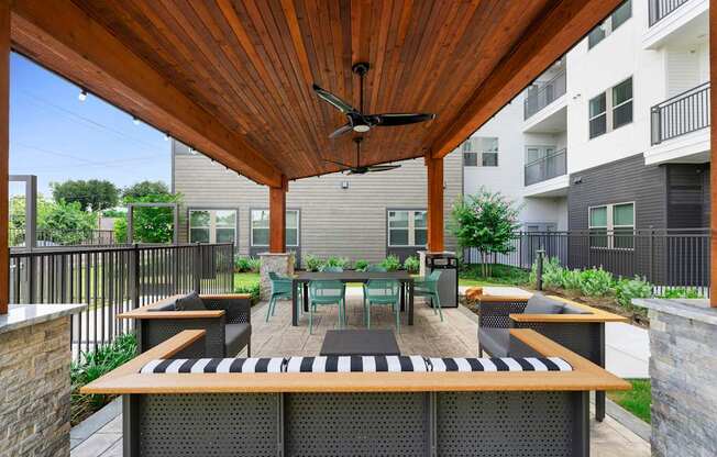 A patio with a table and chairs under a wooden roof.