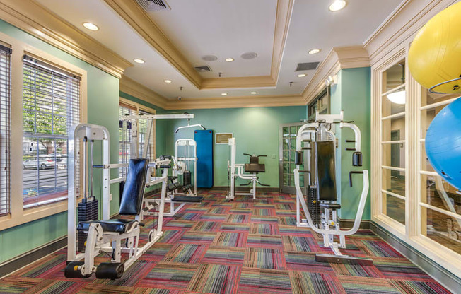 a fitness room with weights and cardio machines and a window