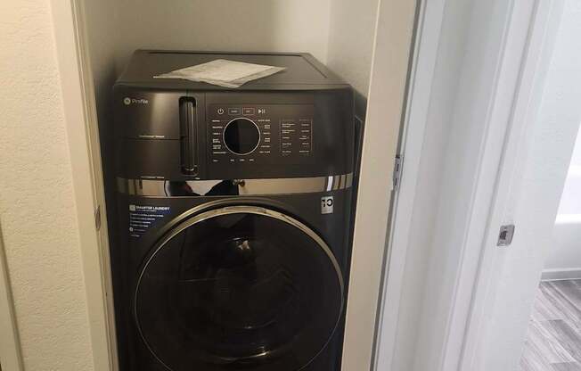 A black microwave oven is sitting on a wooden floor.