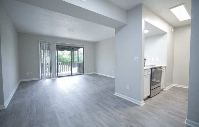 an empty living room and kitchen with a sliding glass door to a balcony