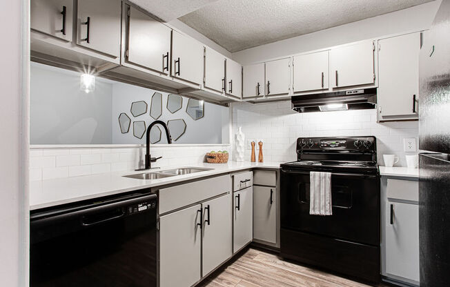 a kitchen with white cabinets and black appliances at Hidden Lake, Union City, GA