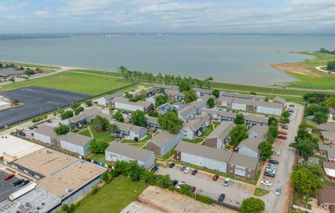 an aerial view of a row of houses with a body of water in the background