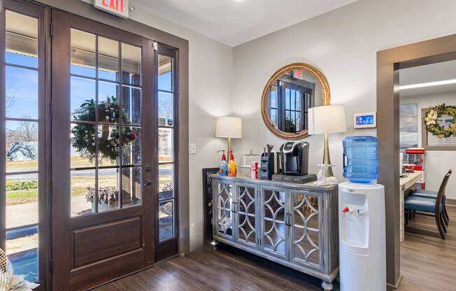 A room with a brown door and a round mirror on the wall.