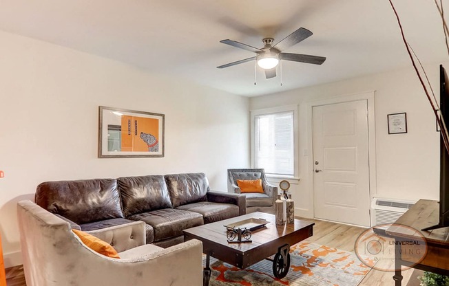 A living room with leather furniture and a ceiling fan.