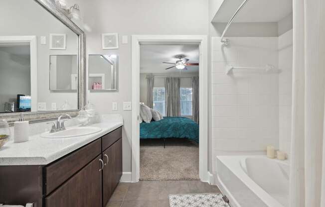 A bathroom with a white tub and a bed in the background.