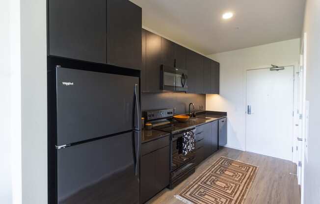 a kitchen with black appliances and a black refrigerator at Analog PDX Apartments, Portland