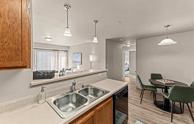 a kitchen with a sink and a dining room with a table and chairs