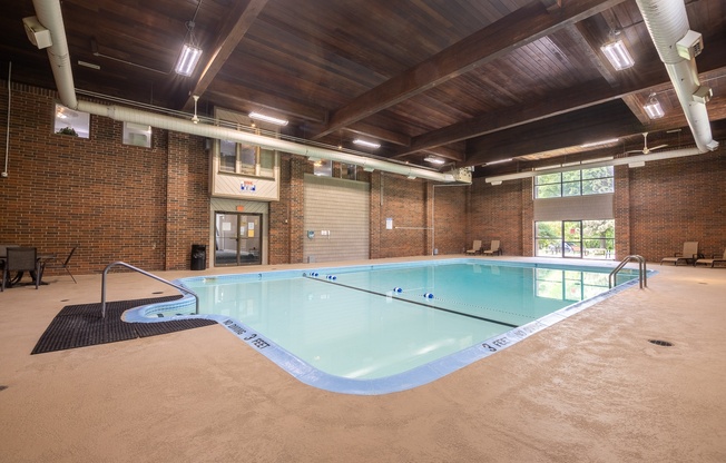 A large indoor swimming pool with a wooden ceiling and brick walls.