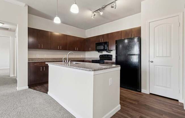 A kitchen with a black fridge and brown cabinets.