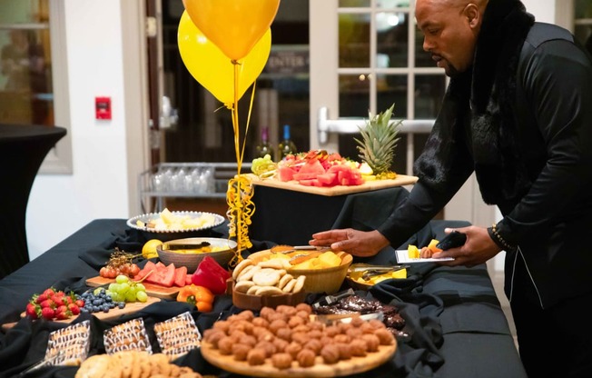 a man selecting food from a buffet table with balloons