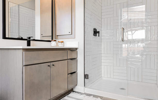 A bathroom with a white tiled shower and a wooden vanity.