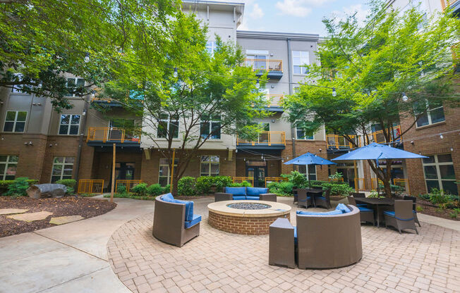 a courtyard with tables and umbrellas in front of an apartment building