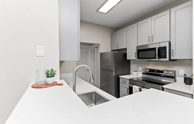a white kitchen with stainless steel appliances and white counter tops