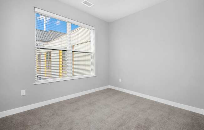 A room with a window and a carpeted floor.
