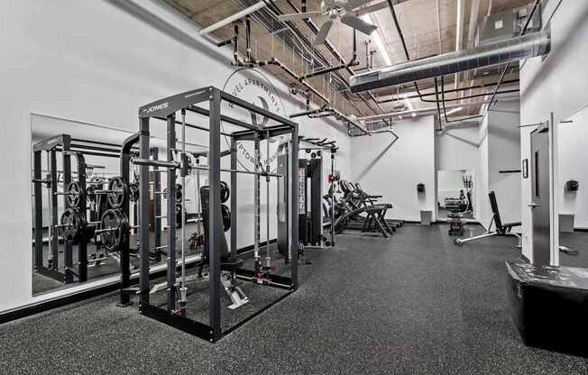 A gym with a variety of equipment including a squat rack, bench, and weights.