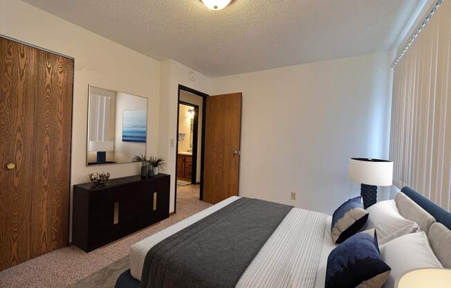 a bedroom with a bed and a dresser and a mirror. Fargo, ND Pacific South Apartments