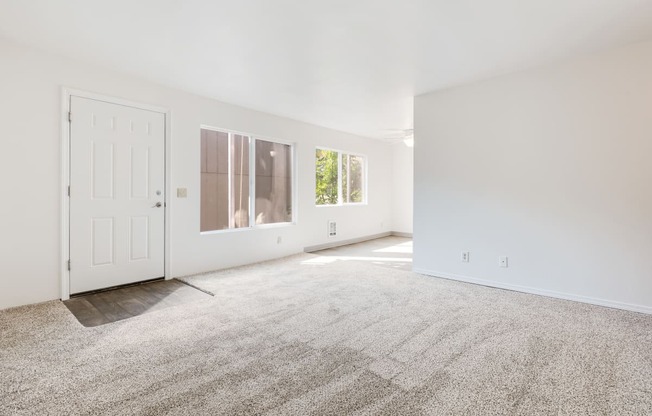 a living room with white walls and carpet and a white door