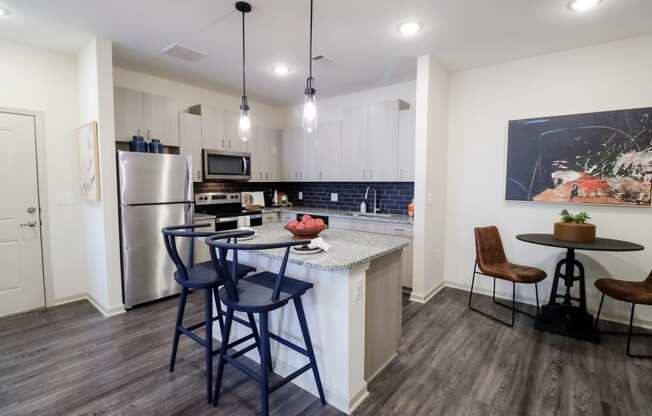 a kitchen with a bar and stools in front of a counter with a sink at The Crest at Acworth, Acworth