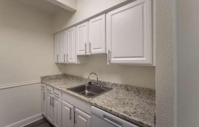 A kitchen with white cabinets in a 2 bedroom, 1 bath apartment home at Harvard Square Apartments in the Vickery Midtown neighborhood of Dallas, TX.