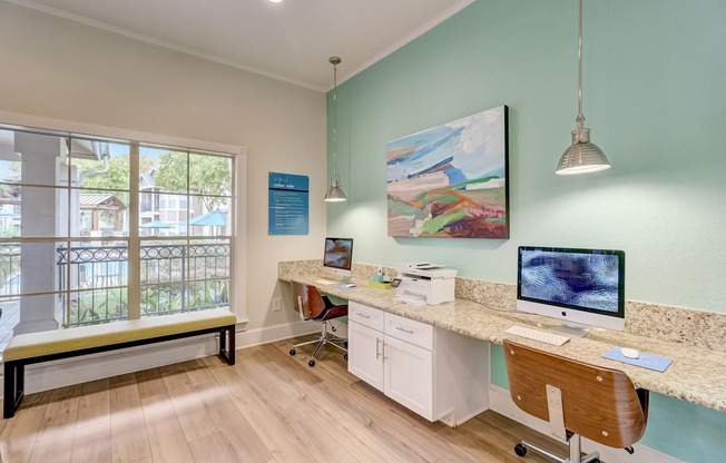 an office with a desk with two computers and a window