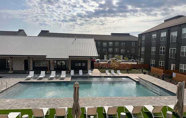 an outdoor pool with chairs and a building