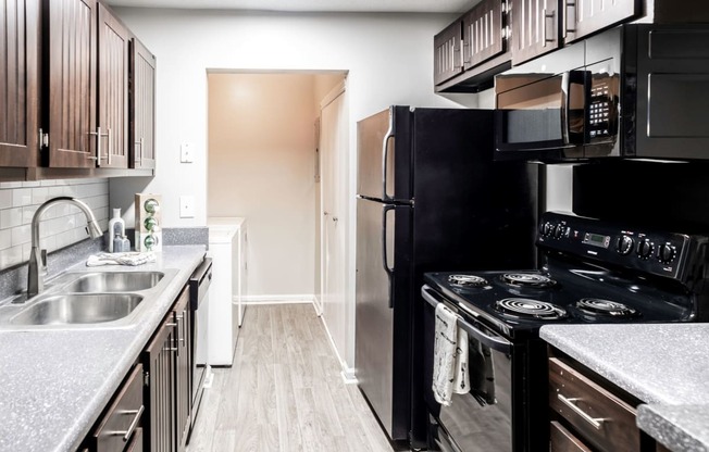 Galley kitchen with black appliances located at Addison on Cobblestone located in Fayetteville, GA 30215