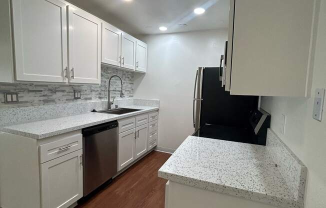 an empty kitchen with white cabinets and a counter top