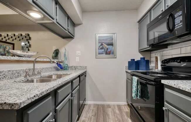 A kitchen with granite countertops and a black stove top oven.