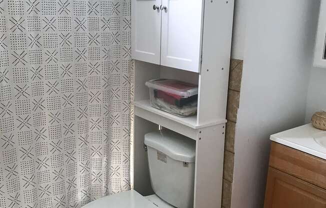 A white toilet with a white cabinet above it in a bathroom.
